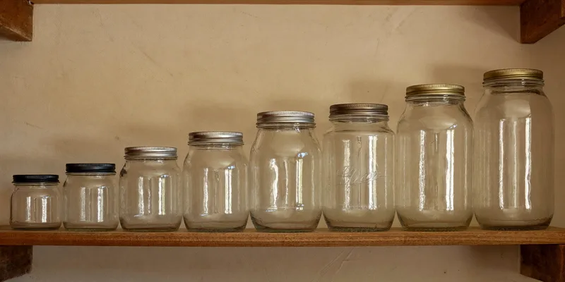 Row of empty canning jars in ascending sizes on a shelf