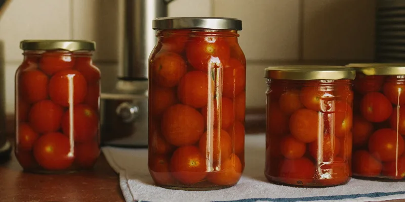 Jar of tomatoes with its lid resting loose and tilted