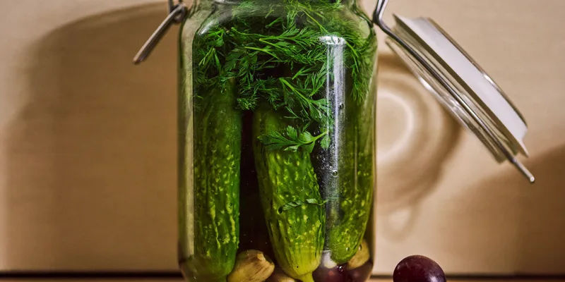 Open jar of crisp pickle spears with dill and garlic