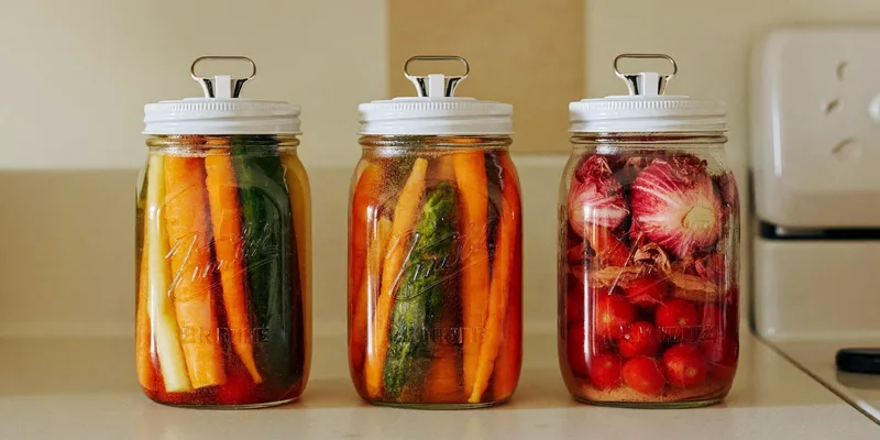 Mason jars with white fermentation lids and colorful vegetables