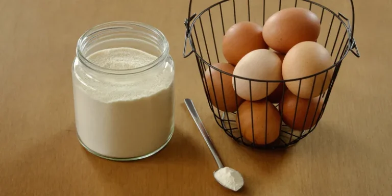 Jar of egg powder beside a wire basket of fresh eggs
