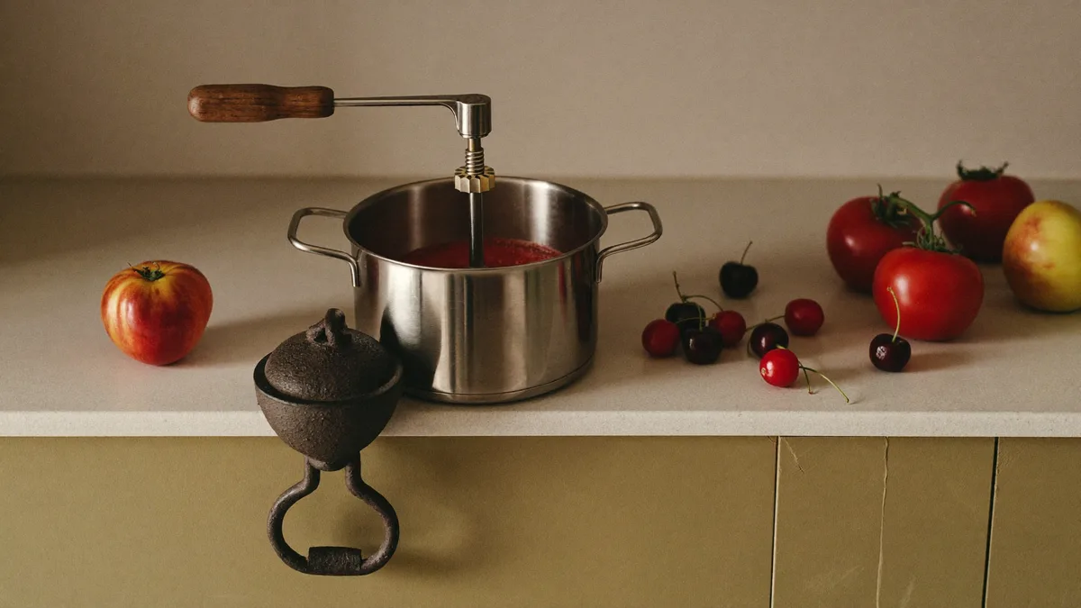 Food mill with tomatoes on a wooden table