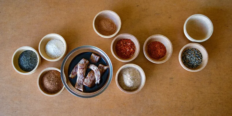 Bowls of spices around a dish of marinating jerky strips