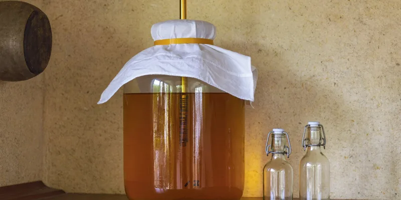 Kombucha brewing jar with cloth cover and swing top bottles