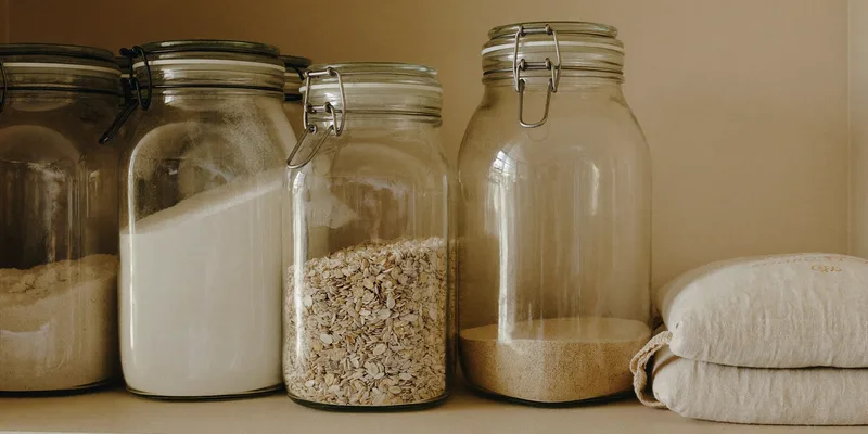 Sealed glass jars of flour, oats and grains on a tidy shelf