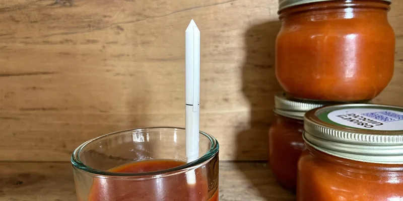 White pen probe standing in a beaker of red sauce