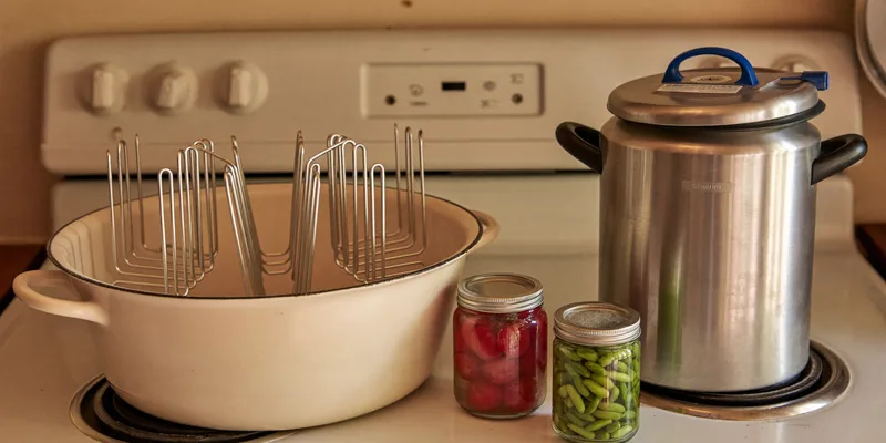 Enamel water bath pot with rack beside a pressure canner